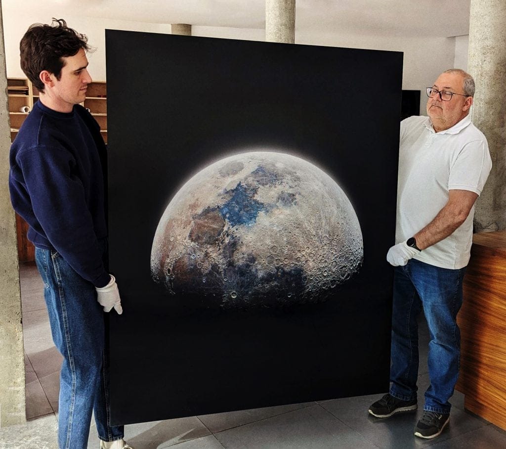 Two people holding a large fine art print representing exclusive, high-value artworks in the new tiered pricing collector funnel.