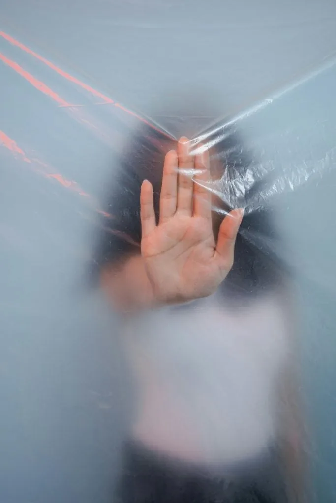 Hand pressed against a translucent surface symbolising artists feeling trapped by pricing fears and common pricing mistakes.